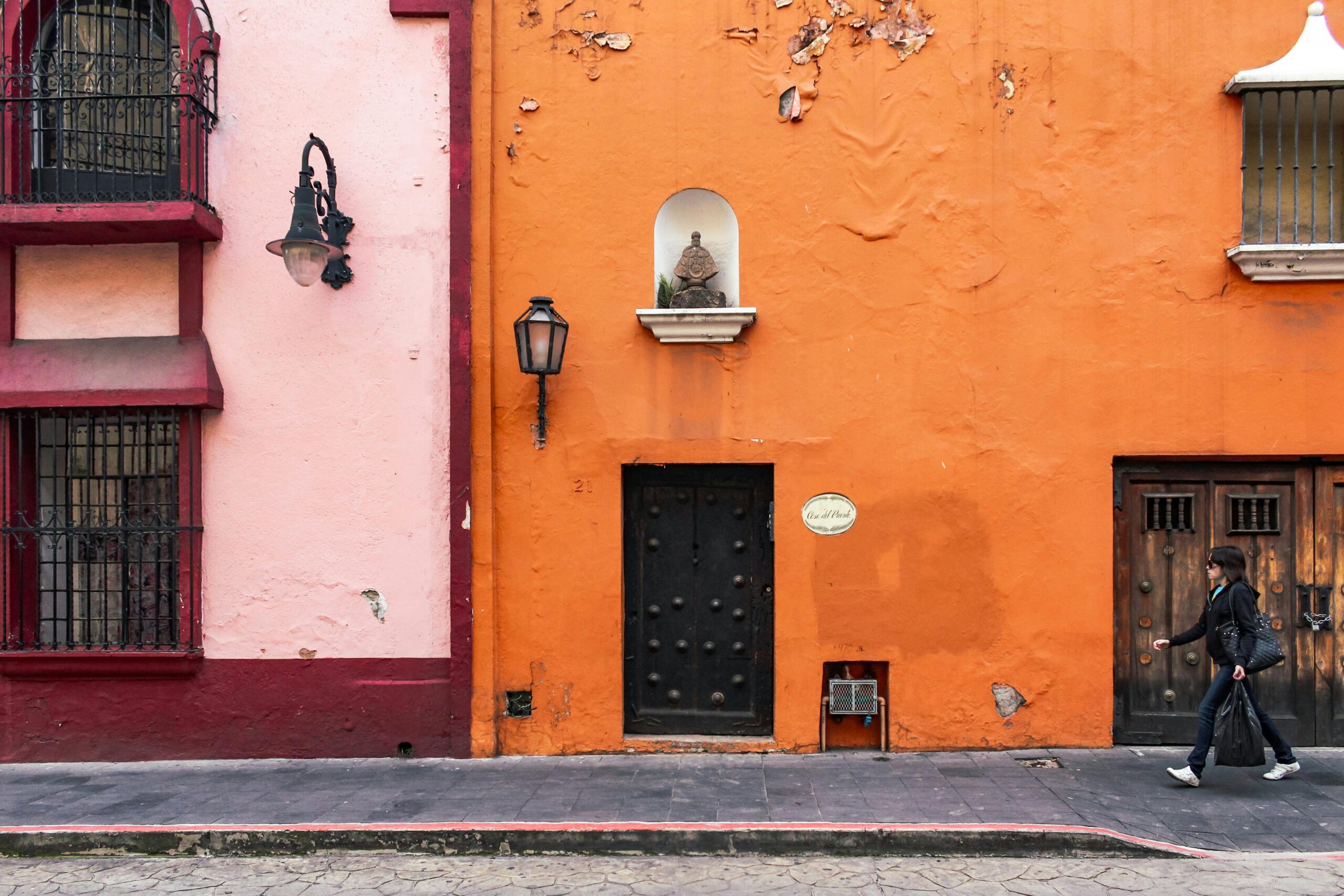 Colorful facade in Cuernavaca with a person walking by on a sunny day.